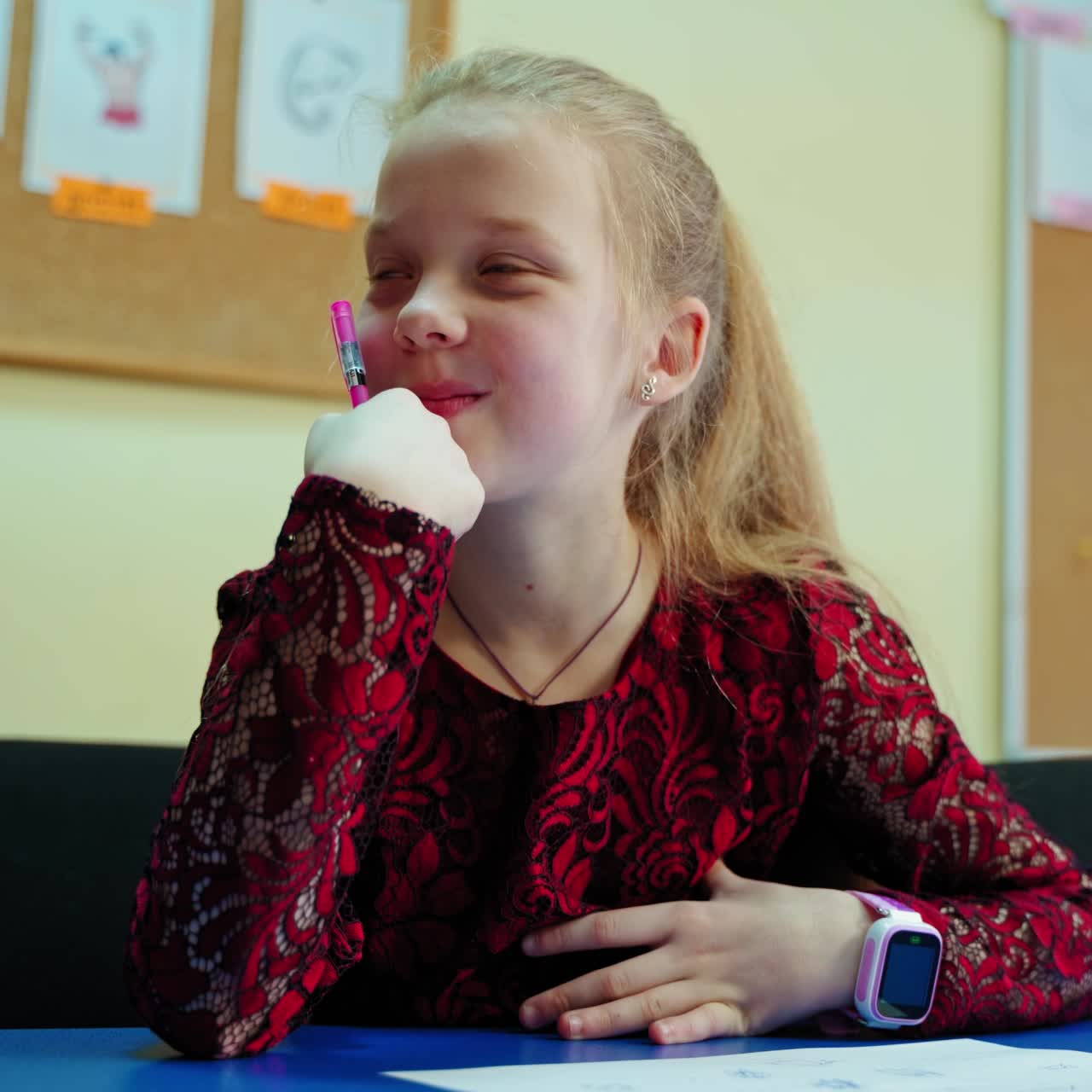 Positive girl in the classroom. Curious little schoolgirl sitting at the desk and listening to the teacher. Portrait of a smiling child at school.