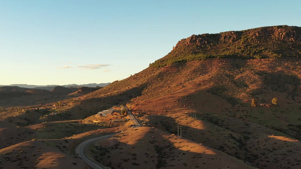 Riprese aeree cinematografiche con drone di un altopiano roccioso di montagna illuminato dalla calda luce dorata del tramonto nel Medio Atlante, Marocco, ideale per progetti di viaggio, avventura e documentari