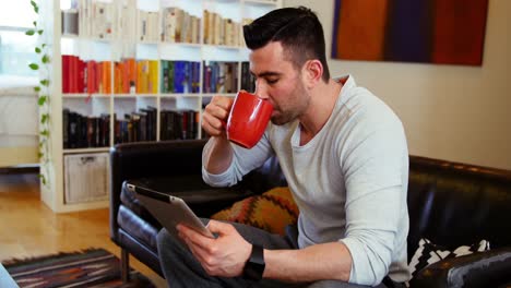 Man-using-digital-tablet-while-having-coffee