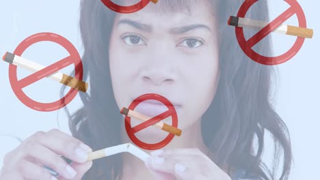 animation of lit cigarettes with no smoking signs over biracial woman breaking cigarette