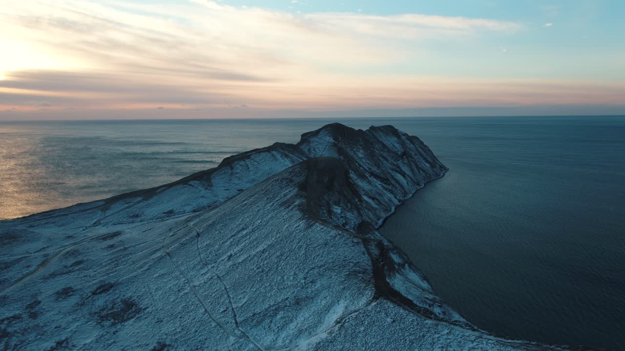 해가 지는 동안 눈 인 산악 케이프