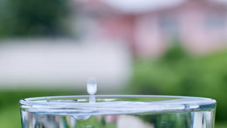 droplets of water are formed as water lands into a glass filled with clean, clear water