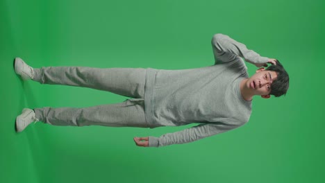 full body of puzzled asian man is standing in front of green screen background