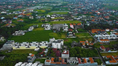 Cinematic-drone-footage-of-Berawa-beach-in-Canggu,-Bali-with-beautiful-landscape,-expensive-hotels,-rice-fields-and-villas-through-calm-weather