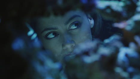 woman looking at colorful fish in aquarium tank watching colorful sea life swimming in corel reef observing marine ecosystem