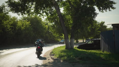 back view of a female biker, her clothes fluttering in the wind as she rides her bike. cars are seen coming in the opposite direction, with view parked cars and building