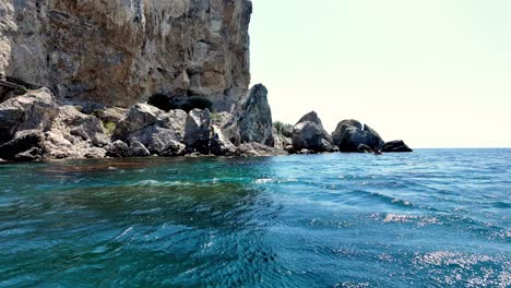 A-scenic-view-of-the-clear-blue-water-surrounding-rocky-cliffs-in-Sudak,-Crimea,-Russia