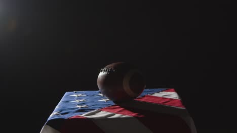 low key lighting studio shot of american football on stars and stripes flag 1