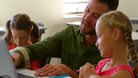 Caucasian-male-schoolteacher-teaching-schoolgirl-at-desk-in-classroom-4k