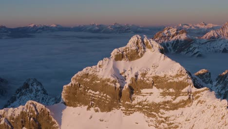 hermoso pico cubierto de nieve pan de drones lateralmente durante la inversión de la puesta de sol en columbia británica