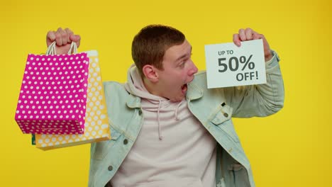 Cheerful-teen-man-showing-shopping-bags-and-Up-To-50-Percent-Off-inscriptions-banner,-Black-Friday