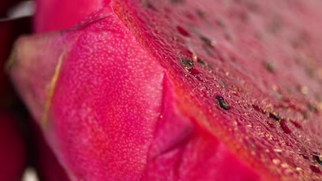 slow motion rotating shot of a dragon fruit sliced in half, revealing its juicy inside and its many seeds