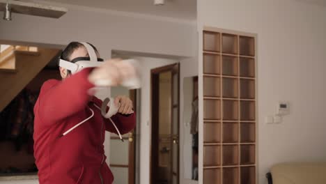 man at home wearing virtual reality headset holding gaming controllers. active vr game virtual reality technology gaming simulation helmets. person fight boxing ar glasses. metaverse oculus technology