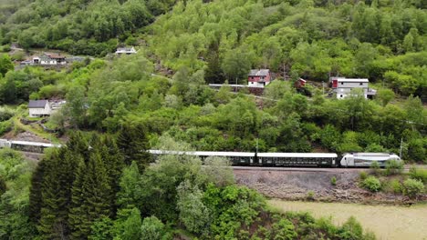 Aerial:-Flåm-train-going-uphill-through-by-a-mountain-side-in-a-valley