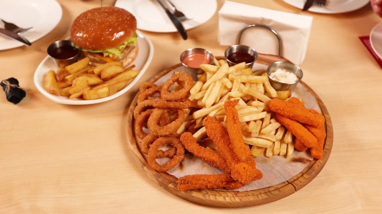 plato de comida con hamburguesas, papas fritas, anillos de cebolla y nuggets de pollo