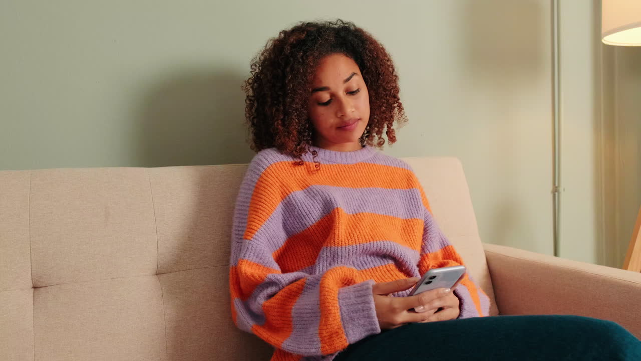 Young Woman Relaxing on Couch and Using Smartphone