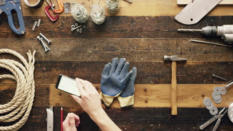 top view artisan craftsman hands using smartphone touchscreen viewing building plans from above - red epic dragon