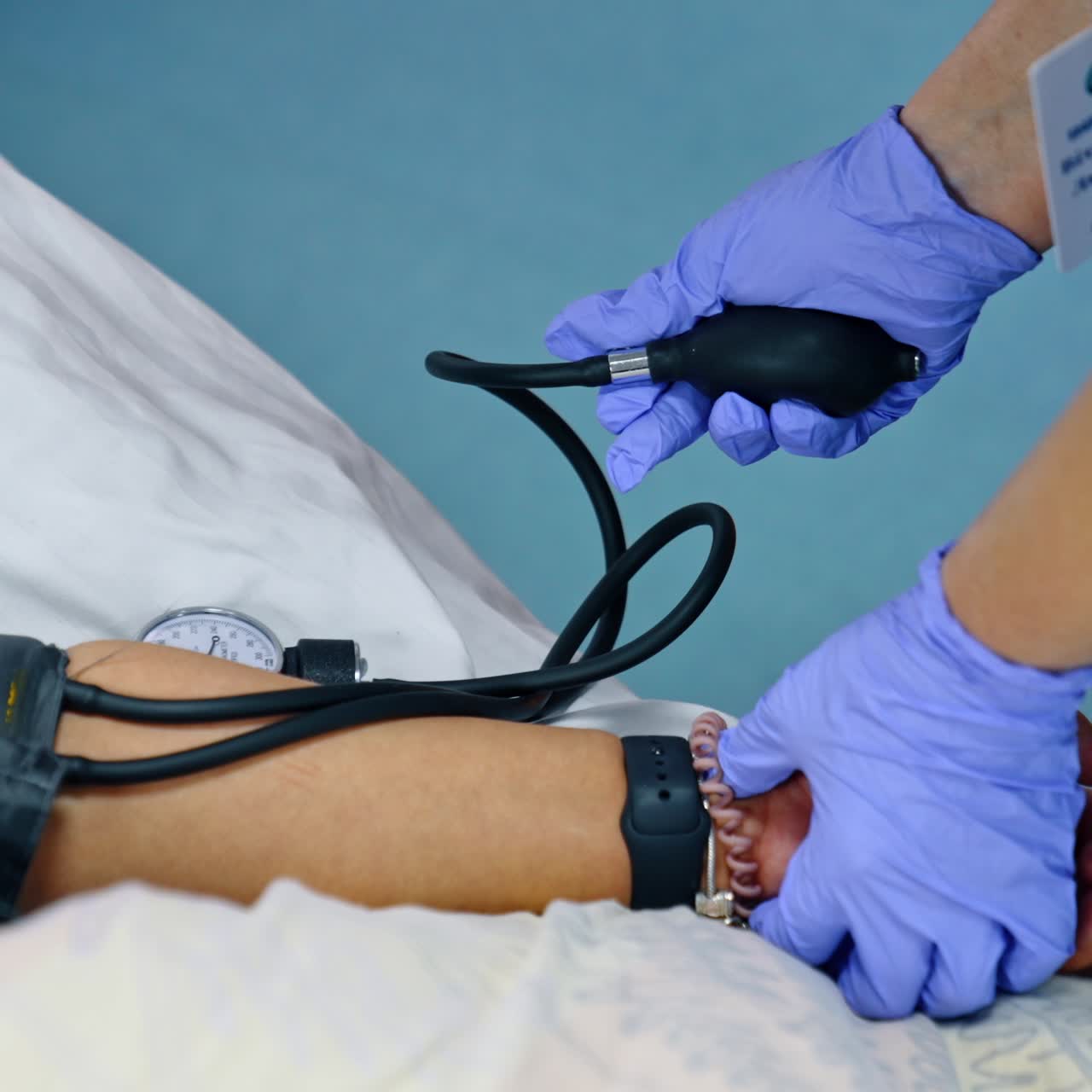 Measuring the pressure for the female patient. Nurse in blue latex gloves uses mechanic blood pressure gauge. Close up