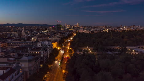 Stürmer-Fliegen-In-Der-Dämmerung-über-Großstadt.-Belebte-Mehrspurige-Straße,-Die-Entlang-Des-El-Retiro-Parks-Führt.-Hyperlapse-Aufnahmen-Mit-Allmählich-Verdunkelndem-Himmel.-Madrid,-Spanien