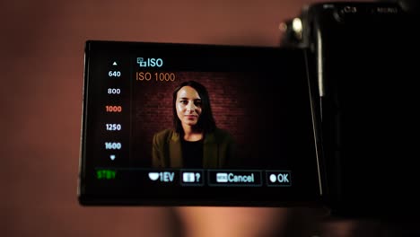 close up of digital camera screen set video recording settings, woman in frame