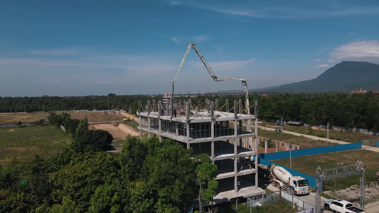 Concrete mixer and large transport arm ensure that employees at the apartment complex under construction can work efficiently in Bokor National Park. Drone lifting shot