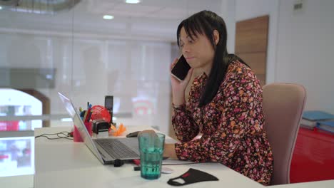 Ethnic-woman-talking-on-smartphone-and-using-laptop