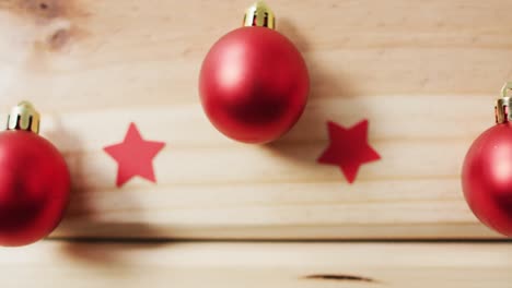 video of red baubles and stars on pale wooden background