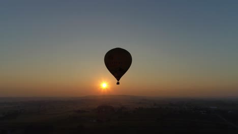 amanecer de un globo aerostático en una mañana nublada sobre tierras de cultivo amish visto por un dron