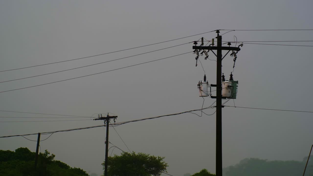 Silhouette of electricity poles and wires against a hazy sky, hinting at infrastructure