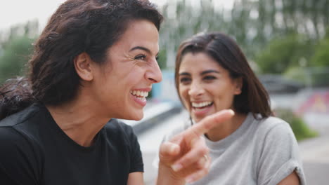 two female friends meeting in urban skate park