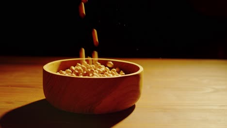 Peanuts or Chickpeas Falling into a Wooden Bowl