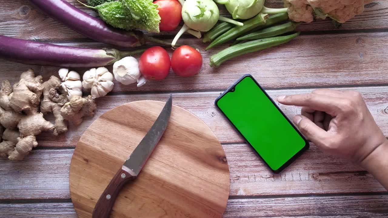 preparar comida con verduras y un teléfono inteligente