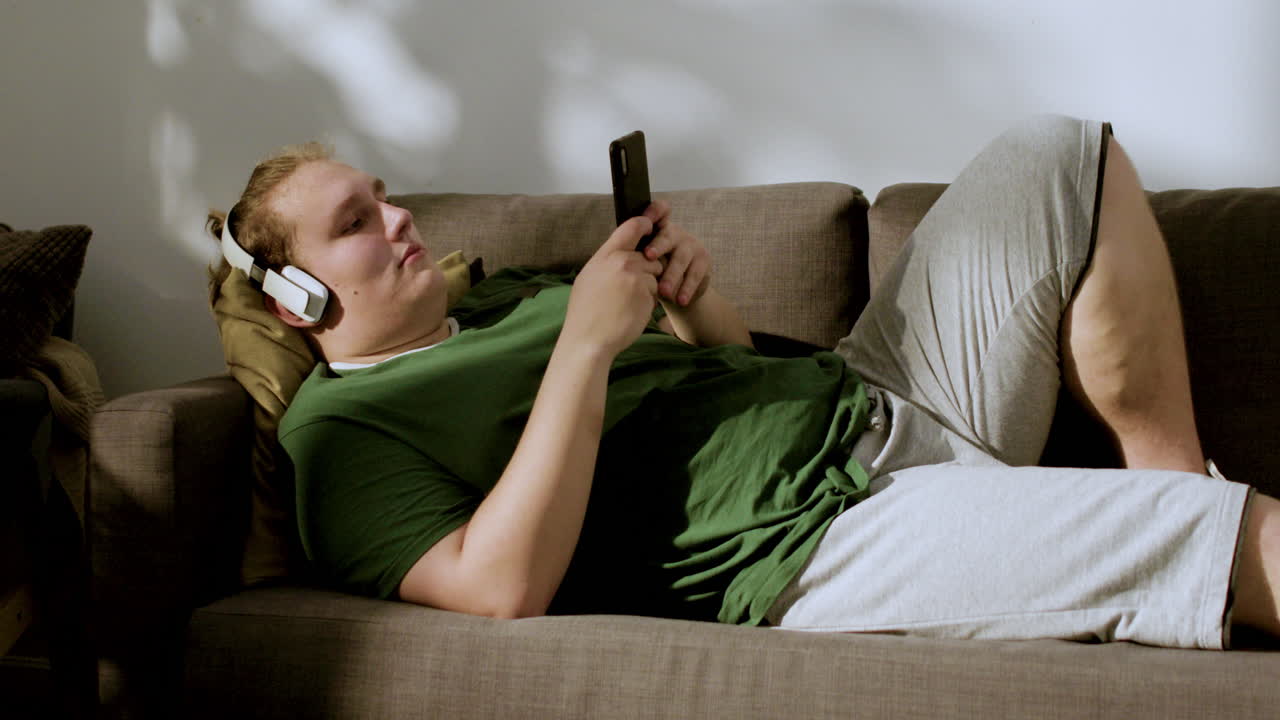 Guy with headphones checking social media at home