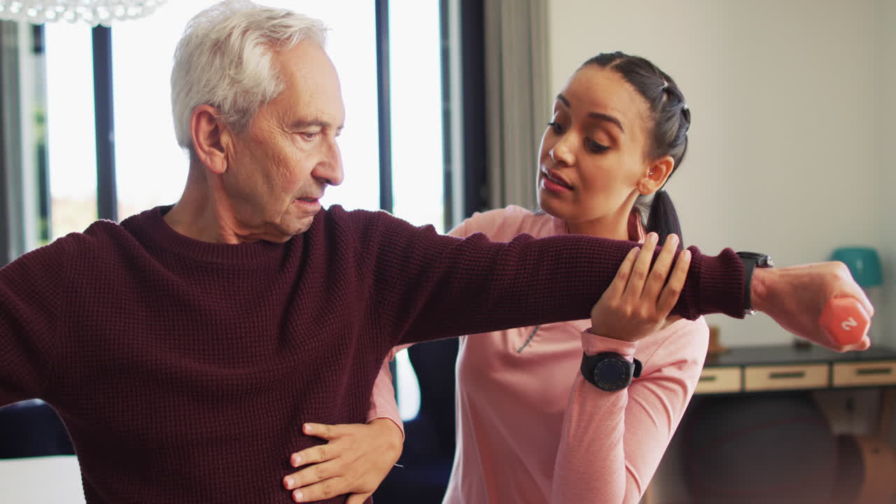 Senior Caucasian man receives assistance from a young biracial female physiotherapist at home