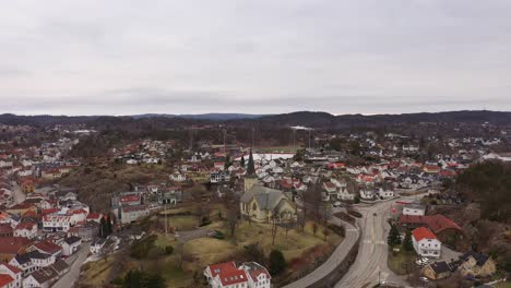 Grimstad-church-and-road-E18-surrounded-by-houses-in-Grimstad-city-center---Aerial-Norway