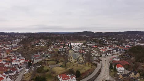 Iglesia-De-Grimstad-Y-Carretera-E18-Rodeada-De-Casas-En-El-Centro-De-La-Ciudad-De-Grimstad---Noruega-Aérea