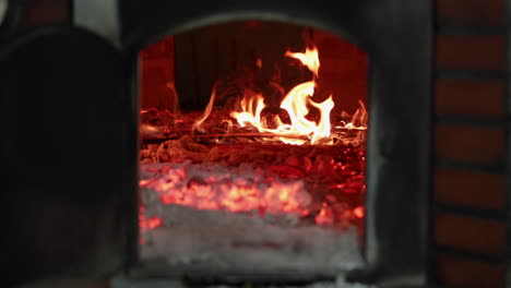 fuego de leña ardiendo dentro de un horno de piedra de ladrillo en una panadería - tiro deslizante