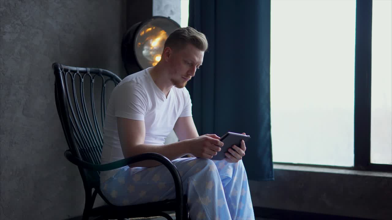 Man relaxing in a rocking chair with tablet