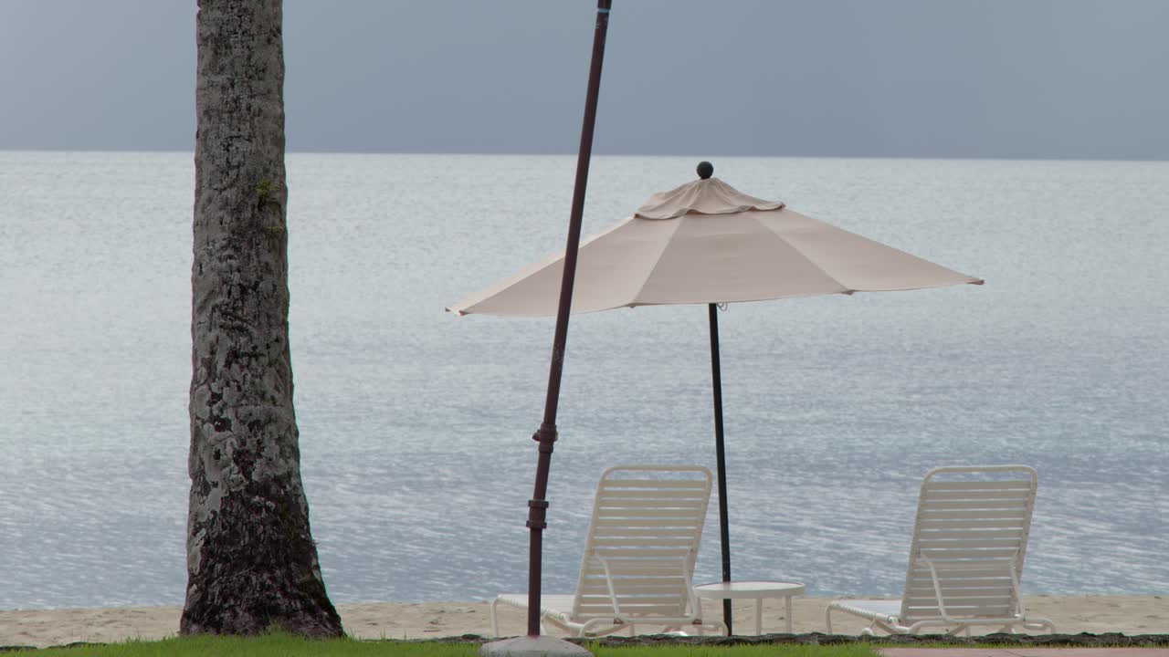 Ampia inquadratura statica di un sereno resort balneare con sedie a sdraio sotto un ombrellone color sabbia