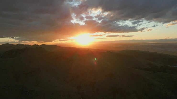 Cielo al atardecer dorado sobre Port Hills, Christchurch, Nueva Zelanda, seguimiento con dron hacia el destello, 4K 60FPS