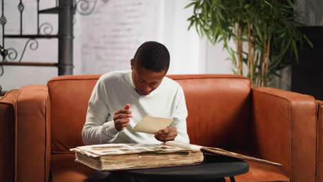 Emotional-African-American-man-looks-at-old-picture-at-home