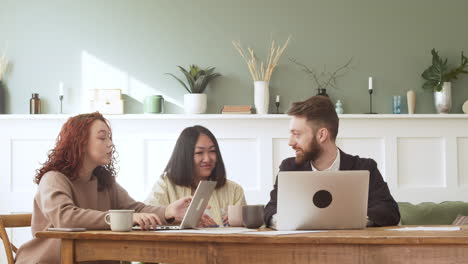 group of three multiethnic colleagues sitting at table and debating while looking laptop computer 1