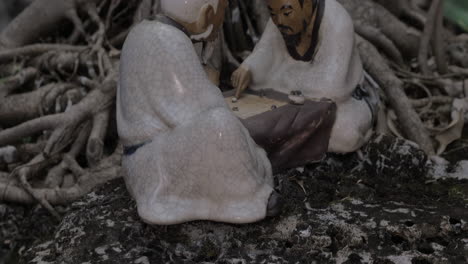 en las raíces de un árbol en la ciudad de hanoi, vietnam, se encuentra una estatuilla de porcelana.