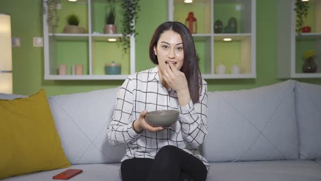 la mujer joven viendo la televisión en casa es feliz y agradable.