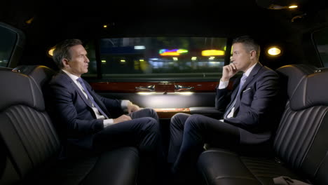 two businessmen traveling in a luxury limousine at night