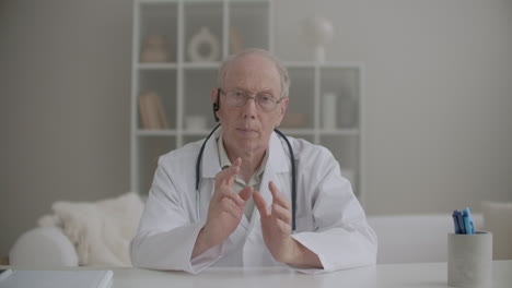 portrait of professor of medicine conducting webinar from his office in clinic aged man is looking at camera and speaking