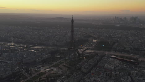 Panoramic-footage-of-city-at-dusk.-Eiffel-Tower-and-surrounding-gardens-along-Seine-River.-Modern-buildings-in-La-Defense-business-district-in-distance.-Paris,-France