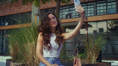 Mujer-Alegre-Haciendo-Selfie-Sentado-En-Un-Banco-De-La-Ciudad.-Chica-Impresionante-Posando-Con-Cámara-De-Teléfono