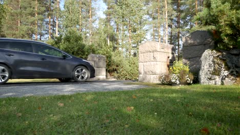 un auto conduciendo a través de la entrada a un cementerio en suecia en un día soleado