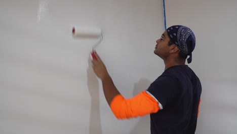 man using roller to paint white color on the wall - close up